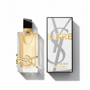 YSL Libre perfume bottle in confident woman's hand with red manicure and gold jewelry against beige background